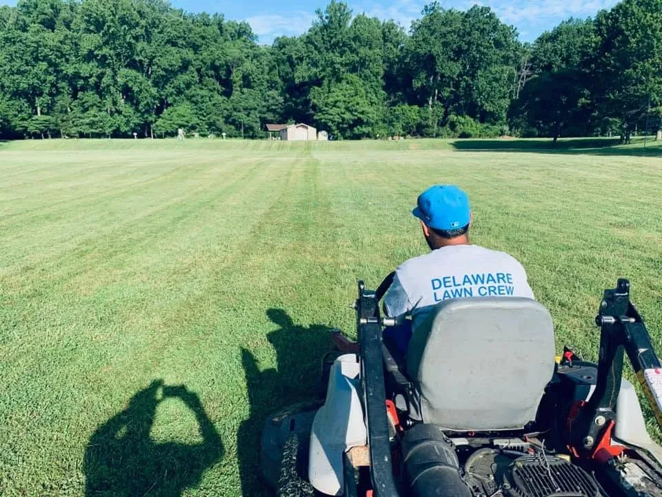 A Delaware Lawn Crew member mowing a wide open field